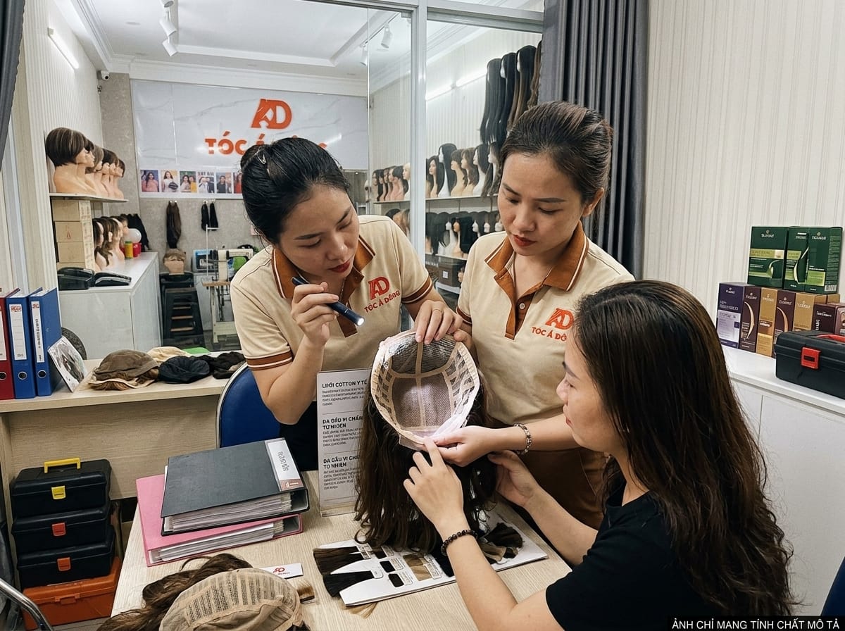 Chuyên viên Tóc Á Đông tỉ mỉ giới thiệu mẫu màng lưới cotton y sinh và cấu trúc siêu da đầu vi điểm cho khách hàng trong phòng tư vấn riêng